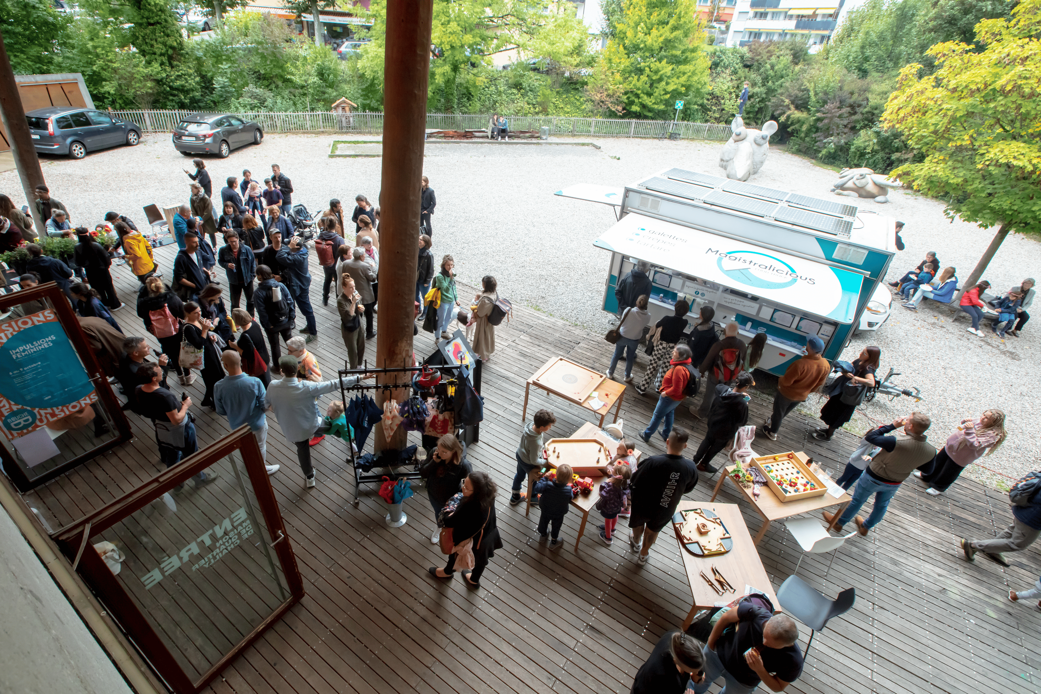 Des gens sont sur la terrasse de la Maison de Quartier de Chailly, discutent entre deux spectacles. Il y a un food truck et des jeux en bois accessibles pour le public. Des gens sont sur la terrasse de la Maison de Quartier de Chailly, discutent entre deux spectacles. Il y a un food truck et des jeux en bois accessibles pour le public.